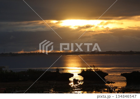 雲の隙間から見える朝陽と海の上の太陽の道と島と対岸の陸の見える風景 134846547