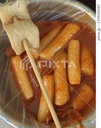 Spicy Korean tteokbokki with chewy rice cakes in a vibrant red sauce, topped with sesame seeds and green onions. A popular street food known for its addictive flavor and satisfying texture. 134846692