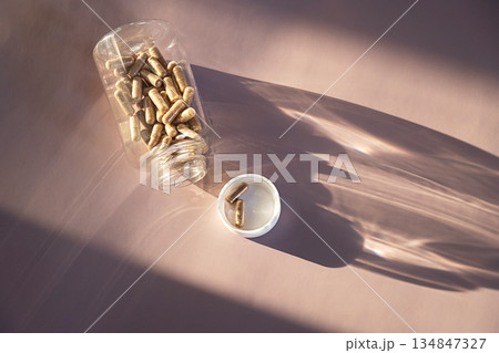 Brown pills in clear plastic bottle and on white cap. 134847327