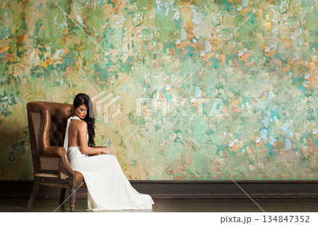 Stylish woman with long hair and make-up sitting in vintage luxurious interior Stylish woman with long hair and make-up sitting in vintage luxurious interior 134847352