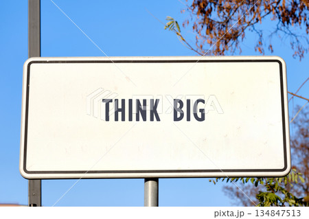 A white rectangular sign stands prominently against a clear blue sky with the inspiring words THINK BIG printed in bold letters. It inspires imagination and reaching potential A white rectangular sign stands prominently against a clear blue sky with the inspiring words THINK BIG printed in bold letters. It inspires imagination and reaching potential 134847513