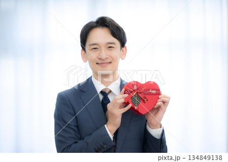ビジネスマンがハート型ギフトを持つ笑顔のプレゼント贈答、バレンタインなど　カメラ目線ありがとう 134849138