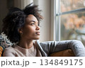 Close-up of a woman sitting on sofa near window 134849175