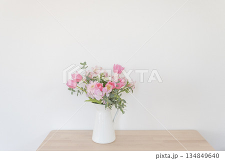 木製の机の上に置かれた春のピンクの花のフラワーアレンジメント 134849640