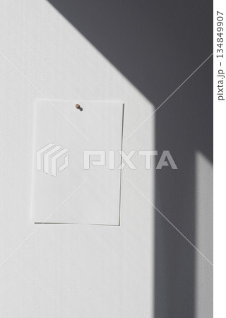 白い壁に貼られた白い紙と黒い斜めの影の背景素材 134849907