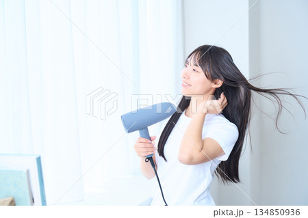 明るいリビングでドライヤーを使う日本人女性 134850936