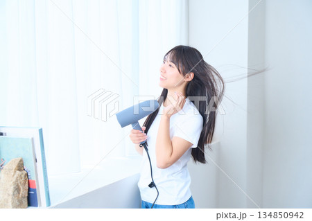 明るいリビングでドライヤーを使う日本人女性 134850942
