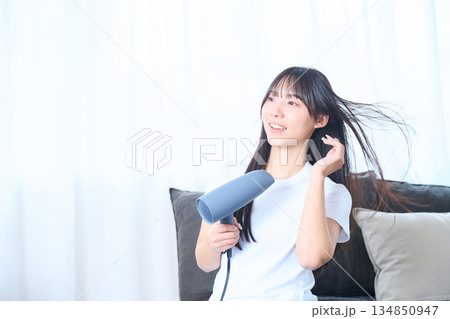 明るいリビングでドライヤーを使う日本人女性 134850947