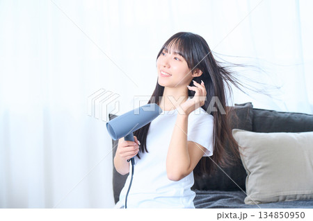 明るいリビングでドライヤーを使う日本人女性 明るいリビングでドライヤーを使う日本人女性 134850950