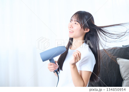 明るいリビングでドライヤーを使う日本人女性 明るいリビングでドライヤーを使う日本人女性 134850954
