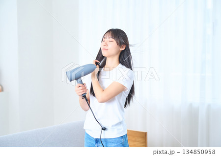 明るいリビングでドライヤーを使う日本人女性 134850958