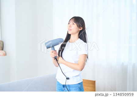 明るいリビングでドライヤーを使う日本人女性 134850959