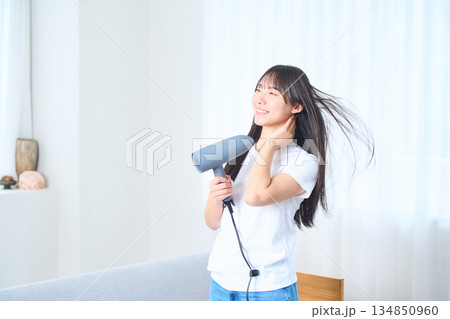 明るいリビングでドライヤーを使う日本人女性 明るいリビングでドライヤーを使う日本人女性 134850960