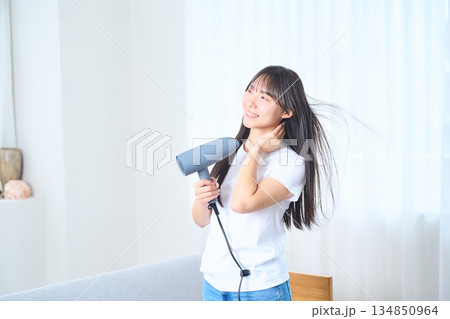 明るいリビングでドライヤーを使う日本人女性 明るいリビングでドライヤーを使う日本人女性 134850964