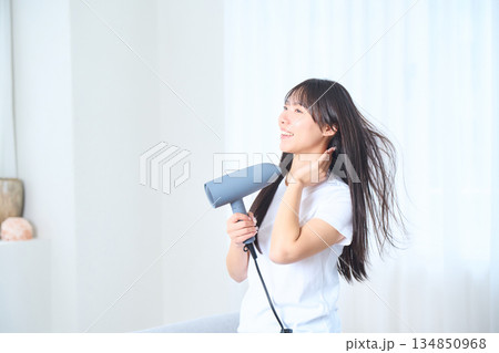 明るいリビングでドライヤーを使う日本人女性 134850968
