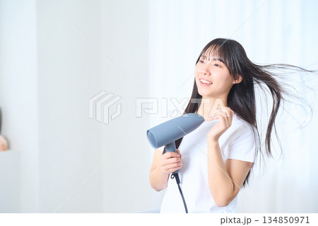 明るいリビングでドライヤーを使う日本人女性 明るいリビングでドライヤーを使う日本人女性 134850971