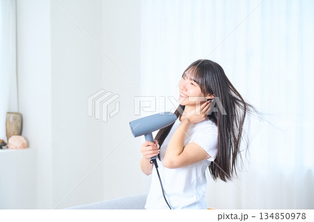 明るいリビングでドライヤーを使う日本人女性 明るいリビングでドライヤーを使う日本人女性 134850978