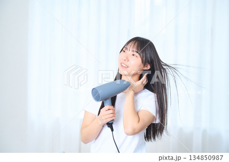 明るいリビングでドライヤーを使う日本人女性 134850987