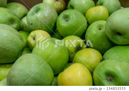 Fresh Green Apples Piled High with Yellow Accents, Vibrant Produce for Market Display Fresh Green Apples Piled High with Yellow Accents, Vibrant Produce for Market Display 134853555