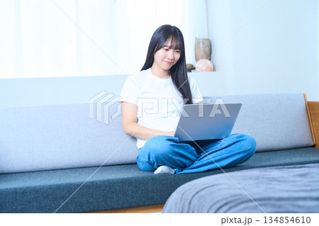 ソファでリラックスしながらパソコンを操作する若い女性 134854610