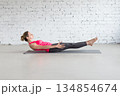 Yoga, Half Boat pose. Fit Caucasian woman practice Ardha Navasana exercise indoor in loft studio. 134854674