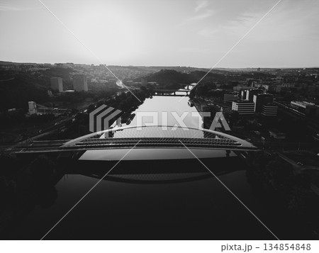 Troja Bridge stands over the Vltava River in Prague as the sun rises. The scene shows the calm waters below and the cityscape in the background. This view captures early morning light. 134854848