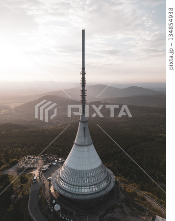 The Jested Mountain Hotel stands prominently amidst the lush landscape in Liberec during a stunning sunset. The Jested Mountain Hotel stands prominently amidst the lush landscape in Liberec during a stunning sunset. 134854938