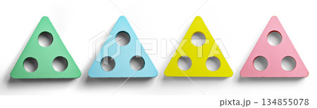 Minimalist pastel colored wooden triangle shapes with three drilled holes arranged on a white background. A simple still life suitable for childhood, learning, and creative play Minimalist pastel colored wooden triangle shapes with three drilled holes arranged on a white background. A simple still life suitable for childhood, learning, and creative play 134855078