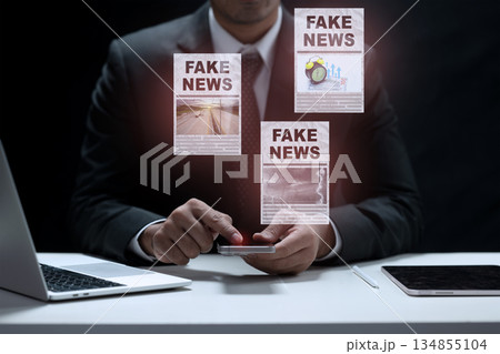 Businessman in a suit uses a smartphone to consume news, and is surrounded by fake news publications on the screen. Concept of fake news Businessman in a suit uses a smartphone to consume news, and is surrounded by fake news publications on the screen. Concept of fake news 134855104
