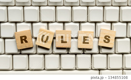 Closeup image of wooden blocks with letters spelling the word "Rules" arranged on a computer keyboard. Concept of rules, compliance, and governance Closeup image of wooden blocks with letters spelling the word "Rules" arranged on a computer keyboard. Concept of rules, compliance, and governance 134855108