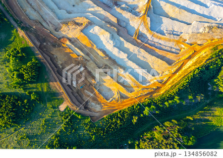 The sandstone quarry at Strelec in Czechia. Workers extract sandstone from the ground while large machinery operates nearby. The landscape features trees and earth moving. 134856082