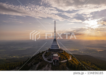 Jested Mountain Hotel stands majestically on a hilltop in Liberec, showcasing its modern architecture against a backdrop of a beautiful sunset. The evening light enhances the scenic views. 134856185