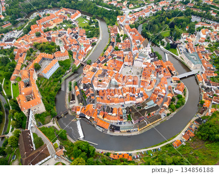 A breathtaking aerial view of Cesky Krumlov, showcasing its charming old town, vibrant rooftops, and the winding Vltava River. The UNESCO site offers a picturesque morning landscape. 134856188