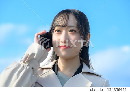 青空を背景にスマホを使用する女性 134856451