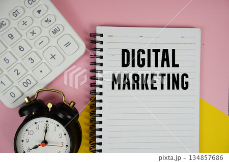 Digital Marketing text written on notepad with calculator and alarm clock on pink background 134857686
