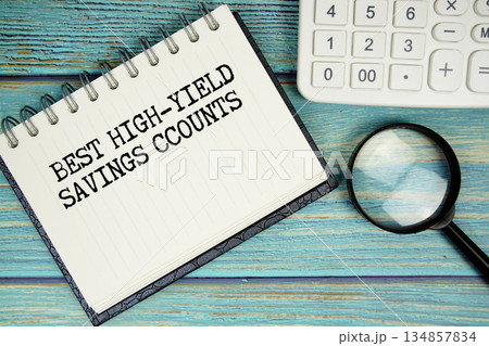 Best High-Yield Savings Accounts text on notepad with magnifying glass and calculator on wooden background 134857834