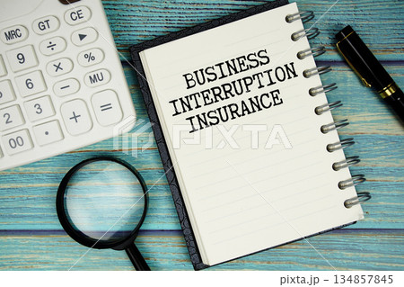 Business Interruption Insurance text on notepad with magnifying glass and calculator on wooden background 134857845