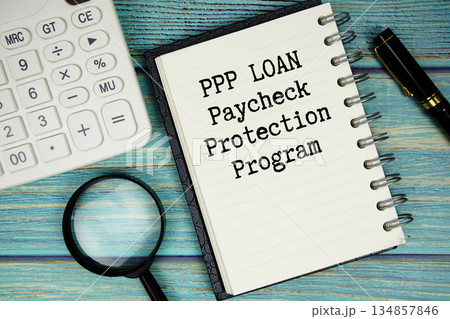 PPP LOAN Paycheck Protection Program text on notepad with magnifying glass and calculator on wooden background 134857846