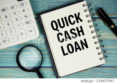 Quick Cash Loan text on notepad with magnifying glass and calculator on wooden background Quick Cash Loan text on notepad with magnifying glass and calculator on wooden background 134857847
