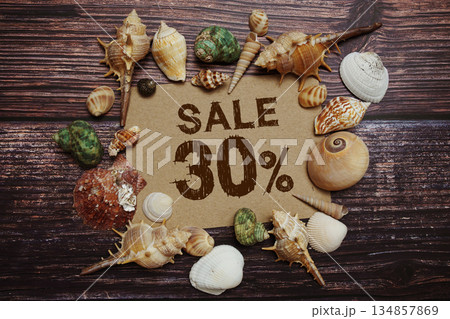 Sale 30% off sign decorated with seashells on a wooden background Sale 30% off sign decorated with seashells on a wooden background 134857869