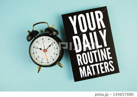 Your Daily Routine Matters text with easel and alarm clock on blue background Your Daily Routine Matters text with easel and alarm clock on blue background 134857890