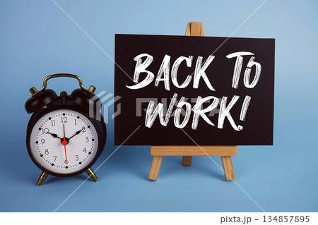 Back To Work! text with easel and alarm clock on blue background 134857895