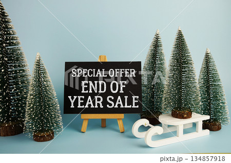 End of Year Sale text with easel and Christmas tree on blue background End of Year Sale text with easel and Christmas tree on blue background 134857918