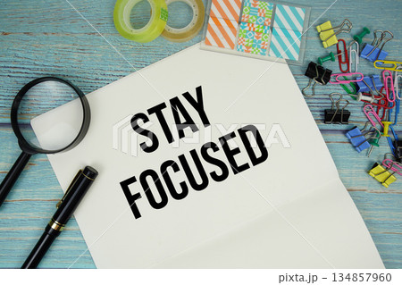 Stay Focused text written on notepad with magnifying glass flat lay on wooden background Stay Focused text written on notepad with magnifying glass flat lay on wooden background 134857960
