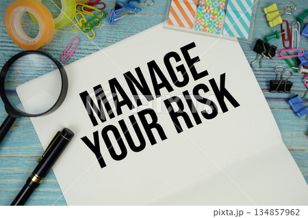 Manage Your Risk text written on notepad with alarm clock and magnifying glass flat lay on wooden background 134857962