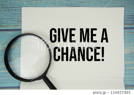Give Me A Chance! text written on notepad with magnifying glass flat lay on wooden background Give Me A Chance! text written on notepad with magnifying glass flat lay on wooden background 134857985
