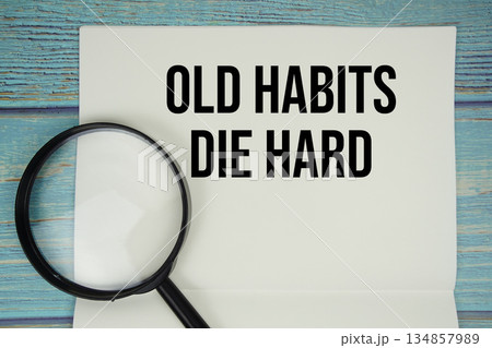 Old Habits Die Hard text written on notepad with magnifying glass flat lay on wooden background Old Habits Die Hard text written on notepad with magnifying glass flat lay on wooden background 134857989