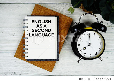 ESL English as a Second Language text written on notepad with alarm clock on wooden background ESL English as a Second Language text written on notepad with alarm clock on wooden background 134858004