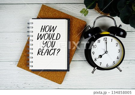 How Would You React? text written on notepad with alarm clock on wooden background How Would You React? text written on notepad with alarm clock on wooden background 134858005
