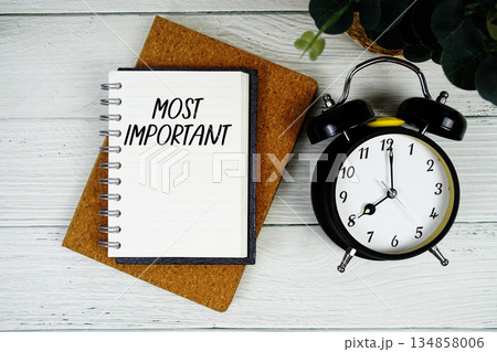 Most Important text written on notepad with alarm clock on wooden background Most Important text written on notepad with alarm clock on wooden background 134858006